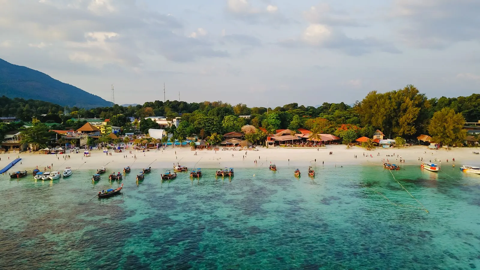 Long beach lined with resorts and longtail boats on Koh Lipe, seen from above