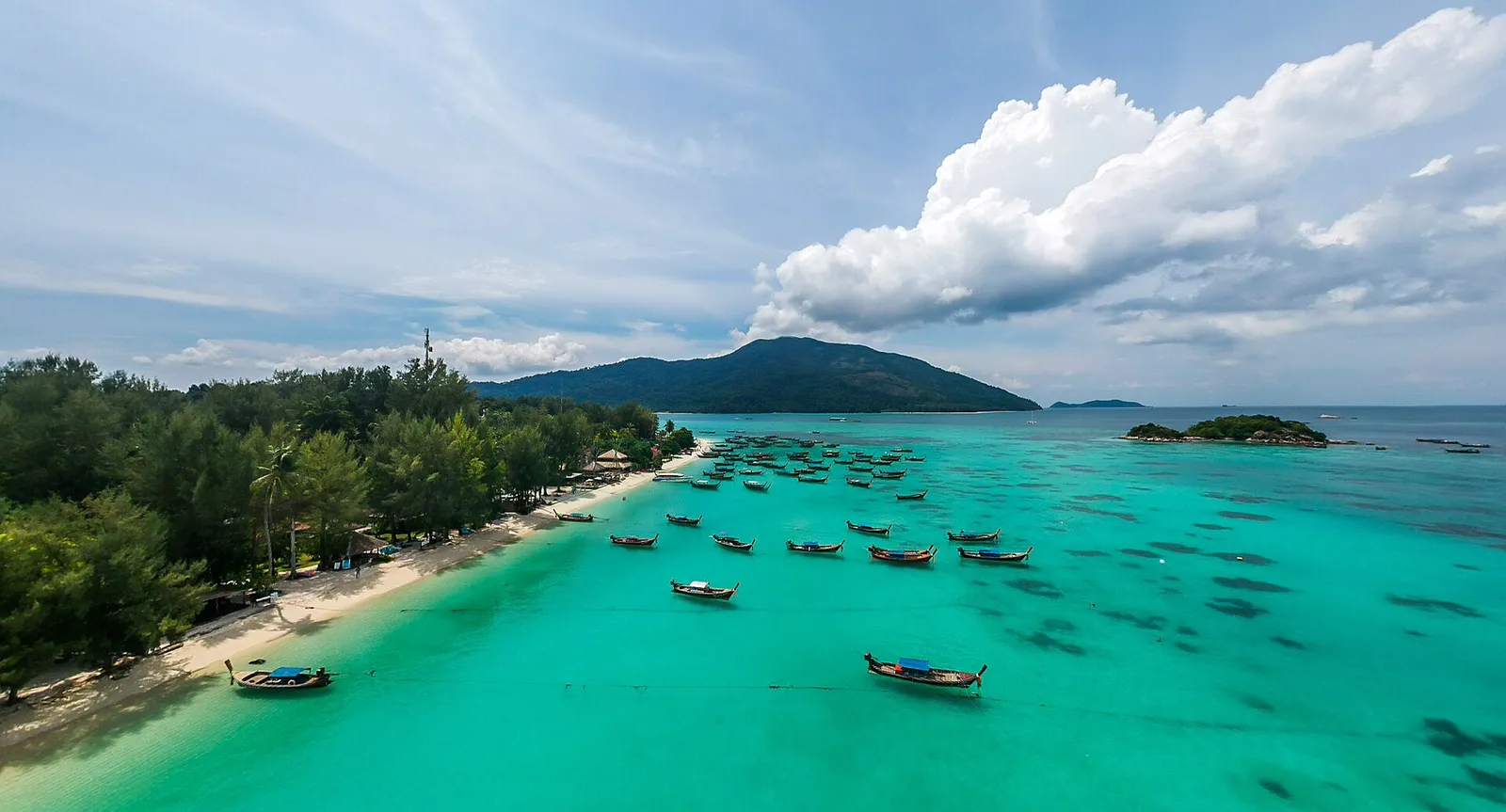 Aerial view along a Koh Lipe beach, longtail boats offshore and Koh Adang behind
